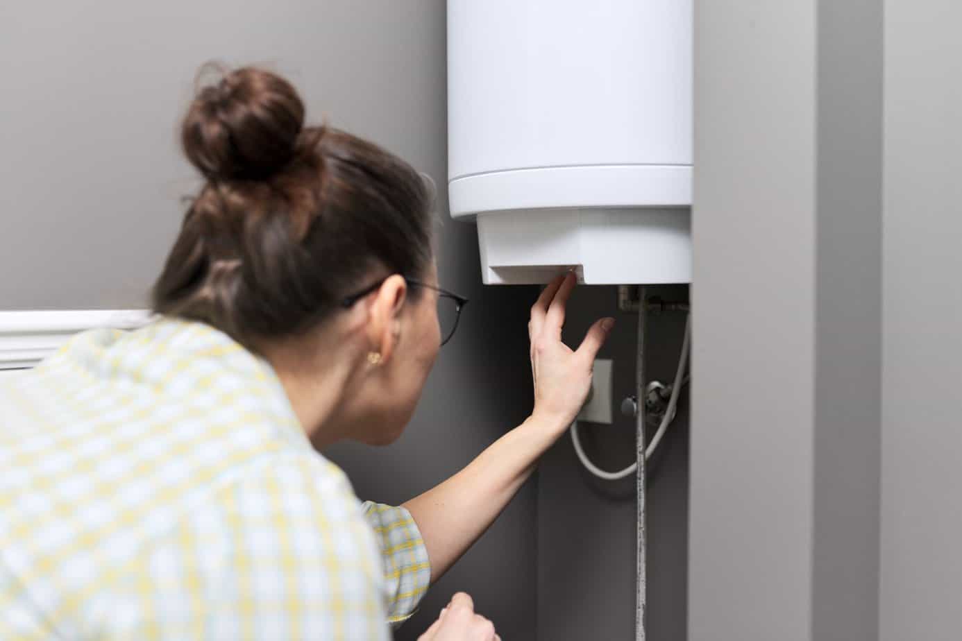woman regulates the temperature on an electric water heater