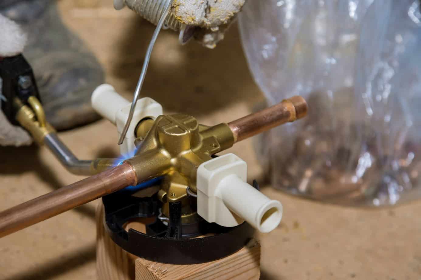 Blue flame torch soldering a brass diverter for shower bathtub