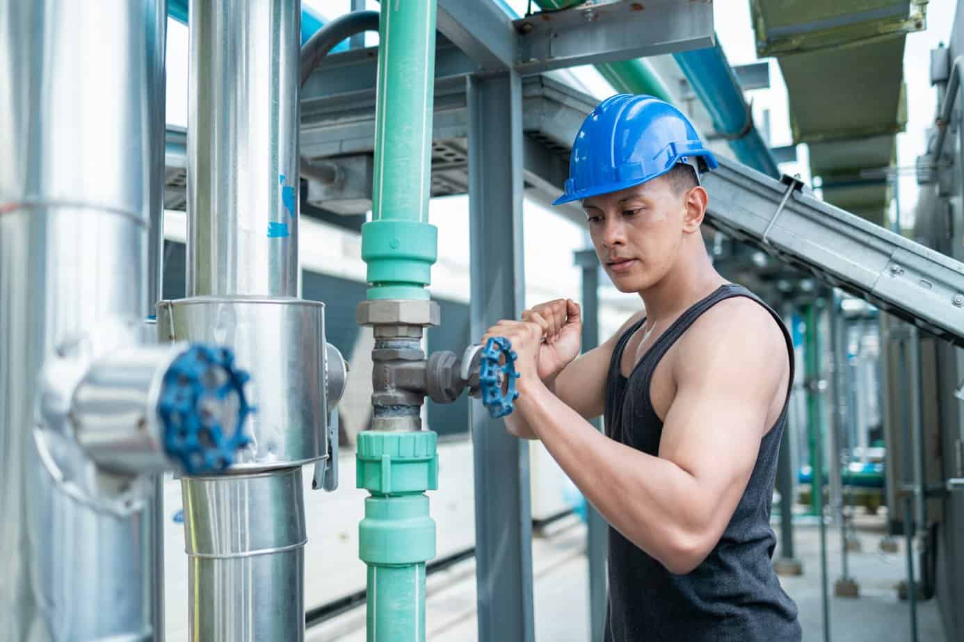 Worker Adjusting Valves at Industrial Pipeline